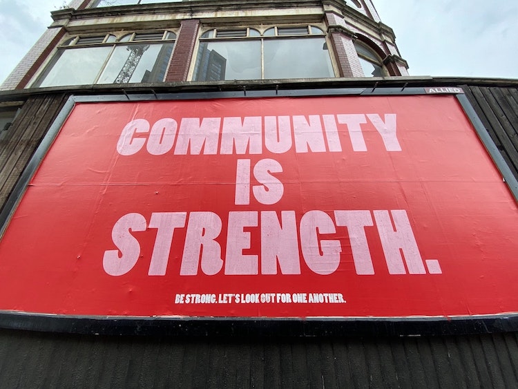 A picture of a sign outside of a building promoting the strength of community.