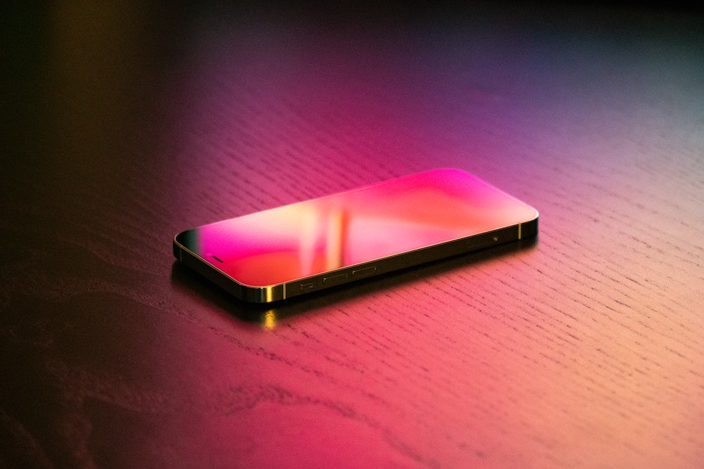 An iPhone on a table at night with light illuminating it