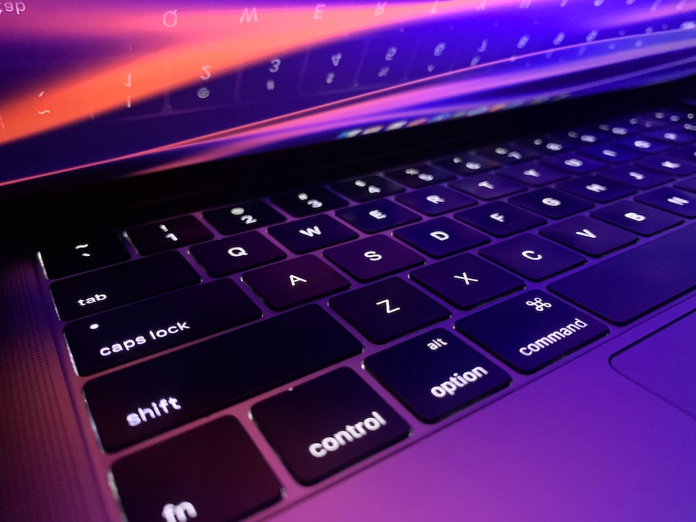 A MacBook Pro screen and keyboard glow at night